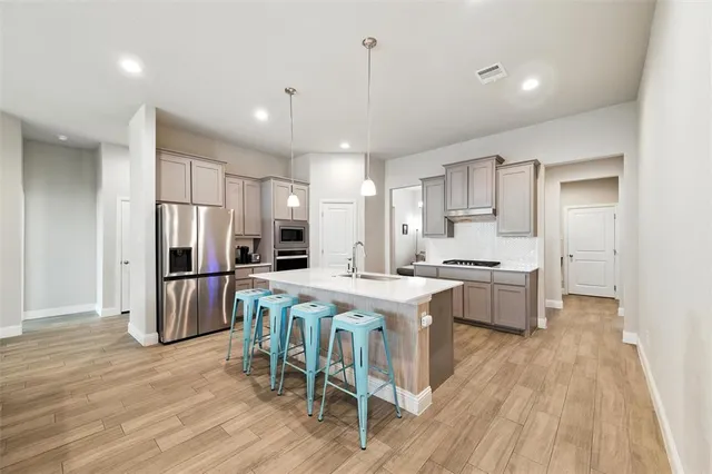 a kitchen with stainless steel appliances a dining table chairs microwave and refrigerator