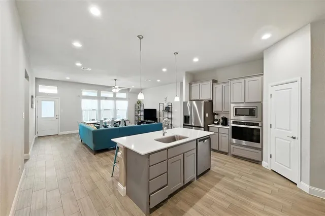 a large kitchen with kitchen island a sink a center island stainless steel appliances and a center island
