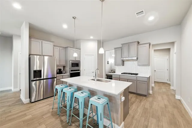 a kitchen with stainless steel appliances a refrigerator a stove a sink a dining table and chairs