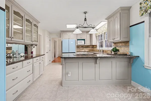 a kitchen with kitchen island granite countertop a sink cabinets and stainless steel appliances