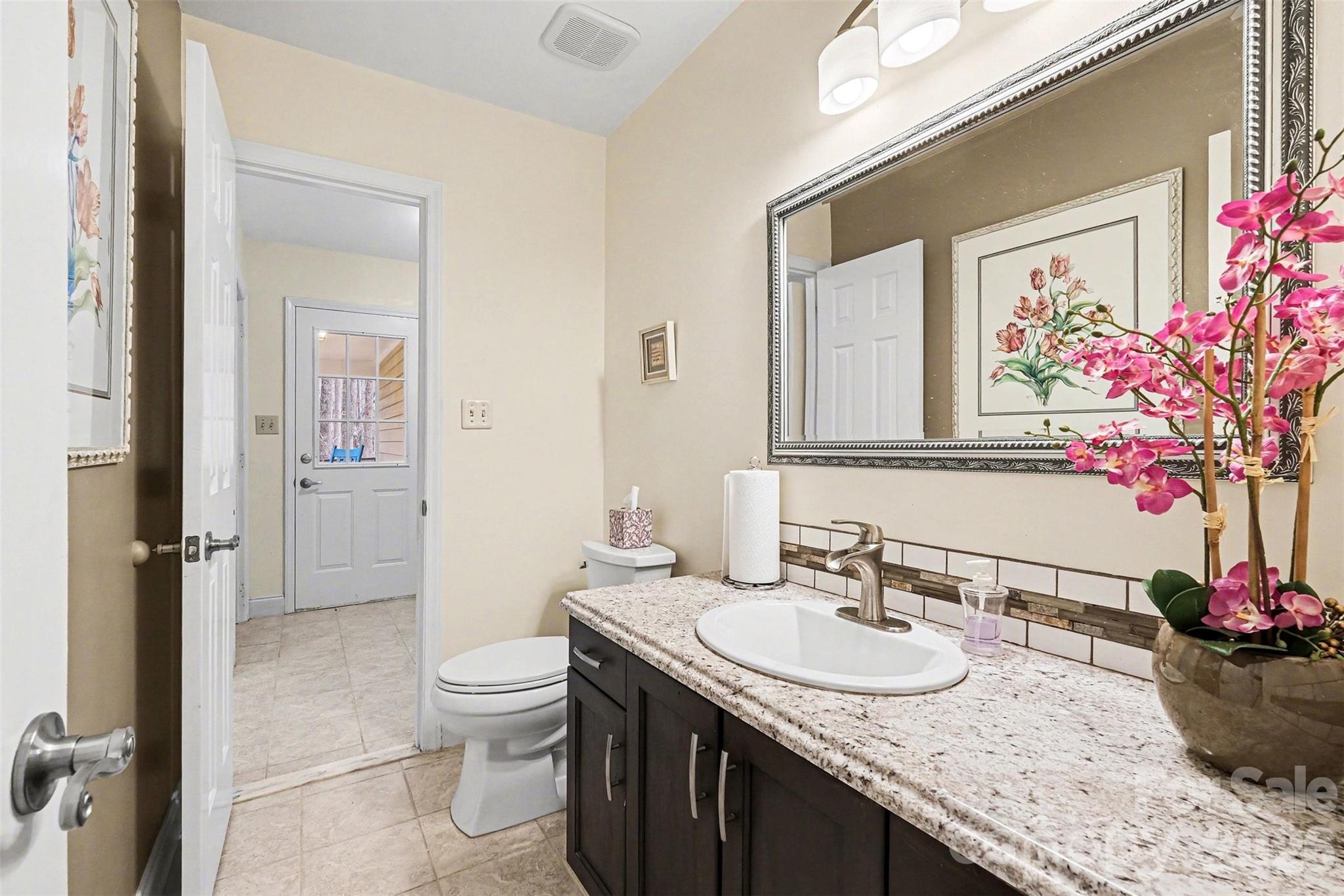 909 Woodland Forest Road Waxhaw, NC 28173 - Photo 6 of 38 a bathroom with a granite countertop sink a toilet and a mirror