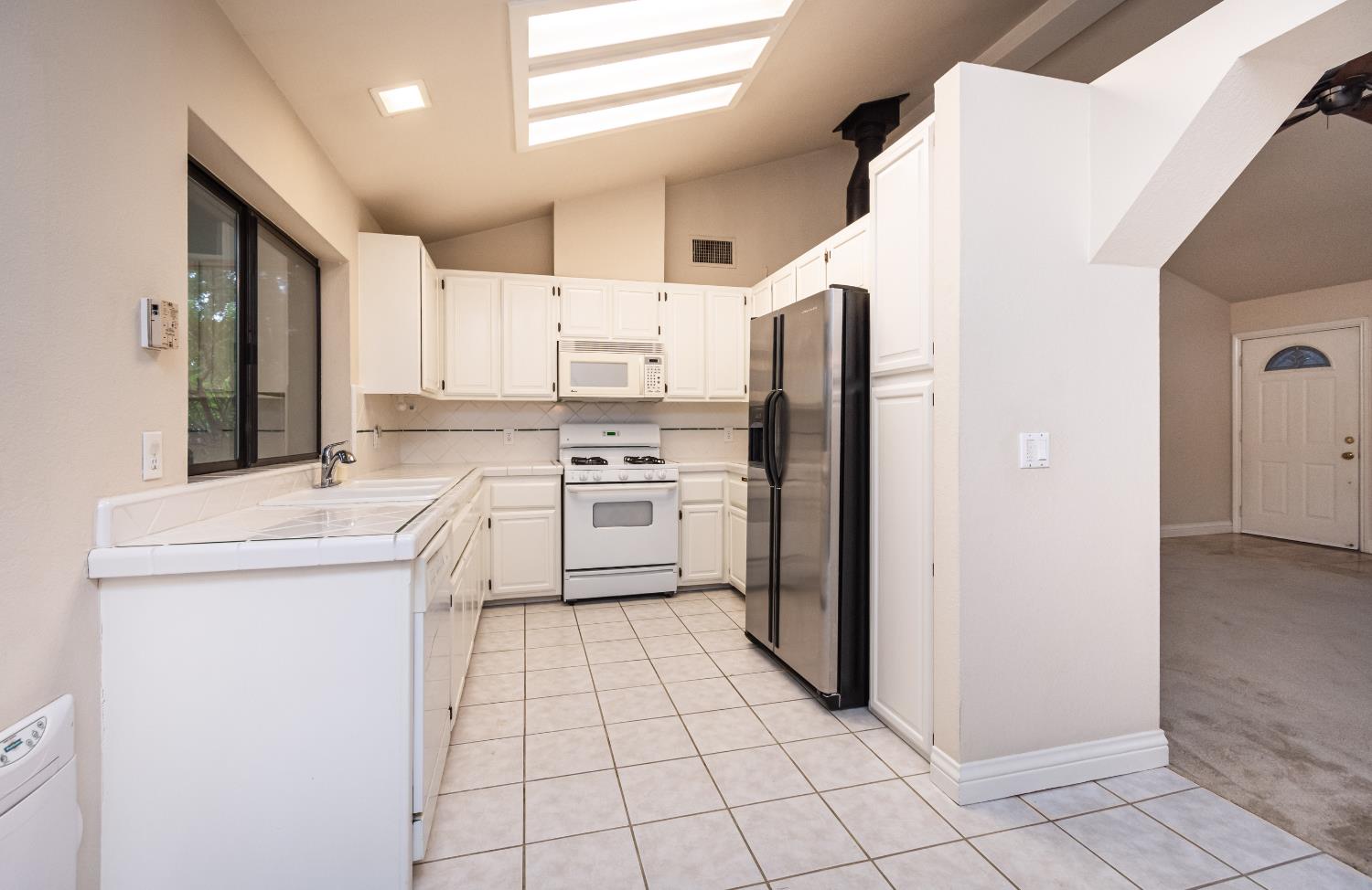 5705 Tudor Way Loomis, CA 95650 - Photo 18 of 59 a kitchen with white cabinets a sink and white appliances