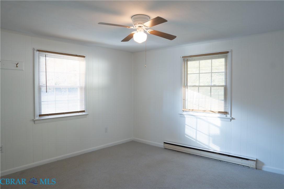 1008 Mill Creek Road Wake, VA 23176 - Photo 21 of 22 Unfurnished room featuring a baseboard heating unit, carpet, ceiling fan, and wood walls