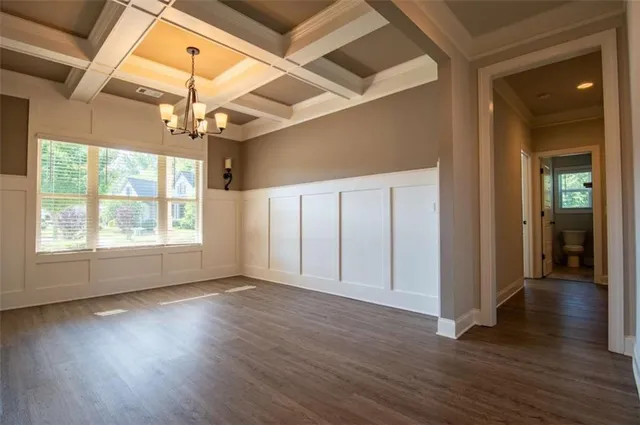 an empty room with wooden floor chandelier and windows