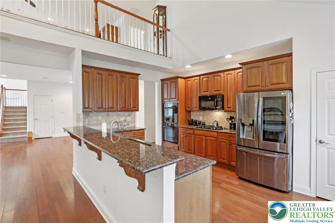 2076 Kingsview Road Lower Macungie Township, PA 18062 - Photo 19 of 53 a kitchen with granite countertop a stove top oven a sink dishwasher and a refrigerator with wooden floor