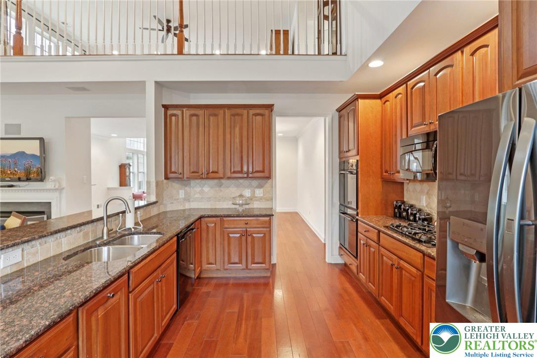 2076 Kingsview Road Lower Macungie Township, PA 18062 - Photo 21 of 53 a kitchen with stainless steel appliances granite countertop a refrigerator a stove a sink and dishwasher with wooden floor
