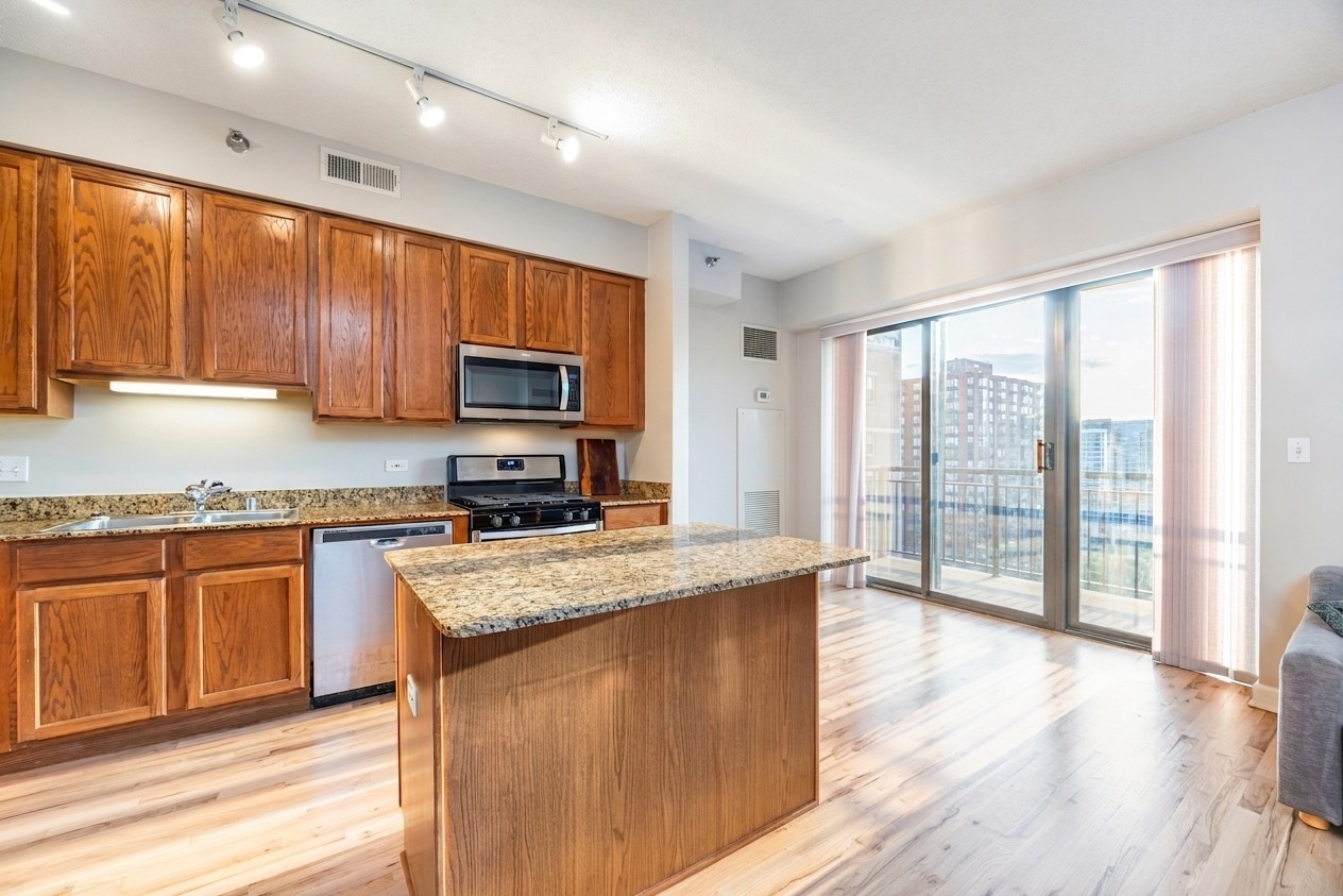 41 East 8th Street, Unit 1805 Chicago, IL 60605 - Photo 4 of 33 a kitchen with stainless steel appliances granite countertop wooden cabinets a stove a sink and dishwasher with wooden floor