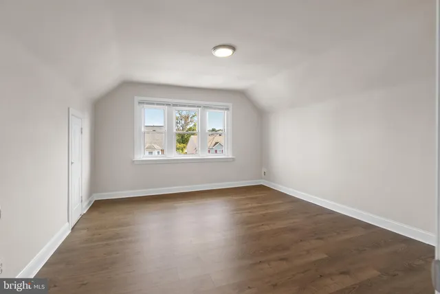 an empty room with wooden floor and window