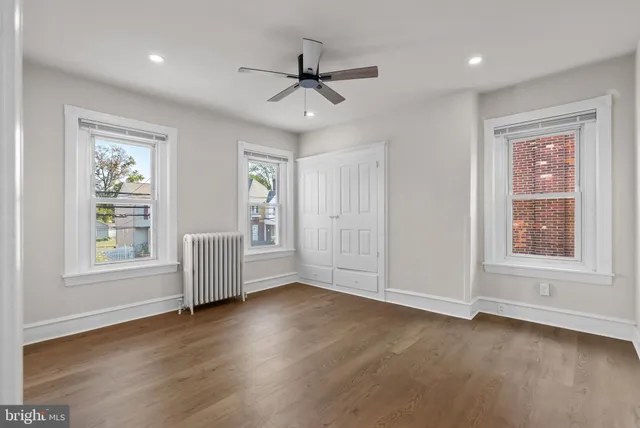 a view of an empty room with a window and wooden floor