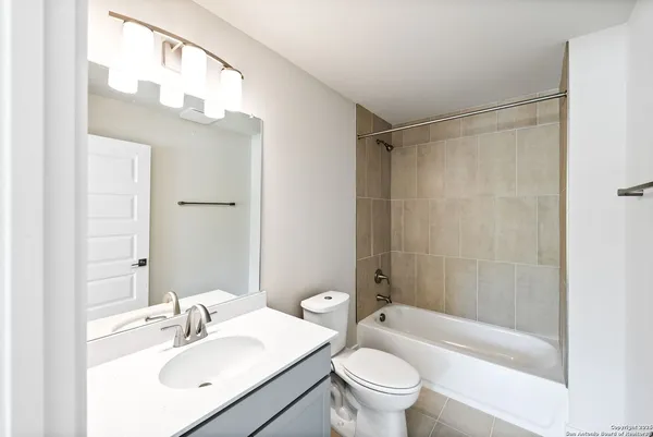 a bathroom with a sink a toilet a mirror a bathtub and shower