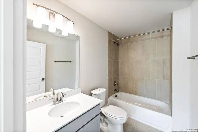 a bathroom with a sink a toilet a mirror a bathtub and shower