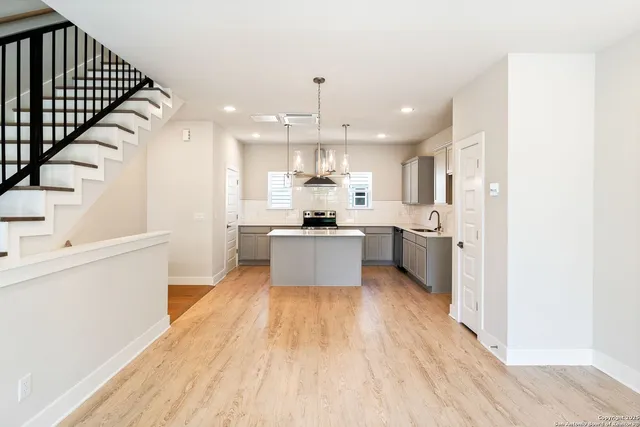 a large kitchen with cabinets wooden floor stainless steel appliances and a dining table