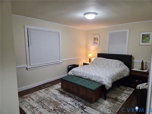 a bedroom with a bed rug and wooden floor