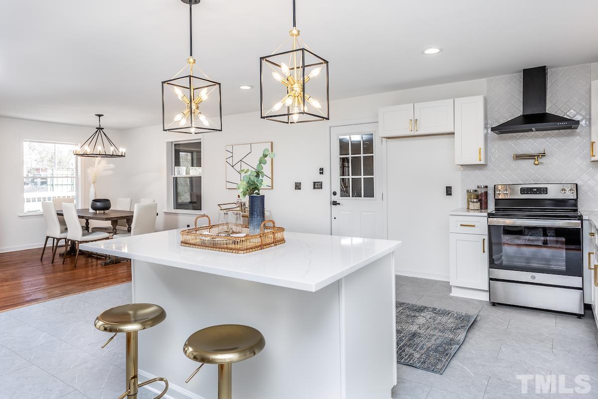 313 Lord Ashley Road Raleigh, NC 27610 - Photo 8 of 32 a kitchen with stainless steel appliances granite countertop a sink a stove a dining table and chairs with wooden floor