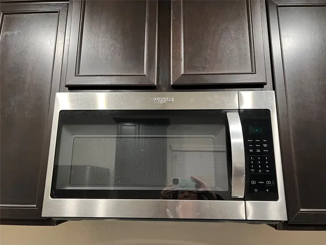 a kitchen with stainless steel appliances granite countertop refrigerator a microwave a sink and wooden cabinets