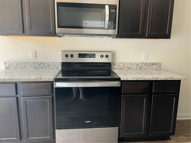 a kitchen with granite countertop cabinets stove and microwave