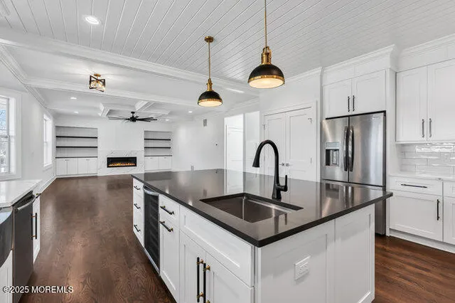 an empty room with wooden floor chandelier fan and windows