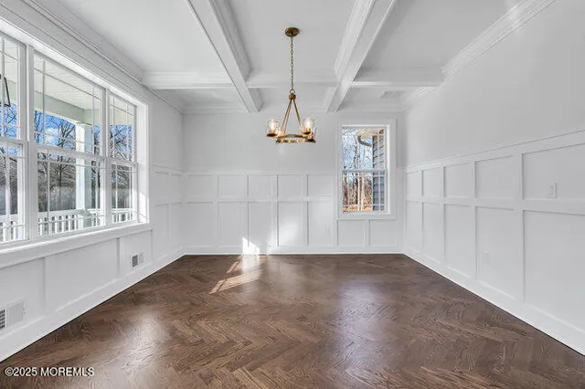 a view of a big room with wooden floor chandelier and windows