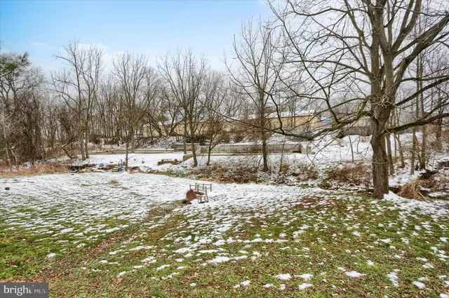 a view of a snow in a yard with large trees