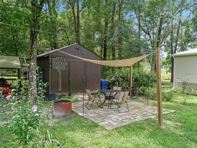 a view of a patio with table and chairs potted plants and large tree