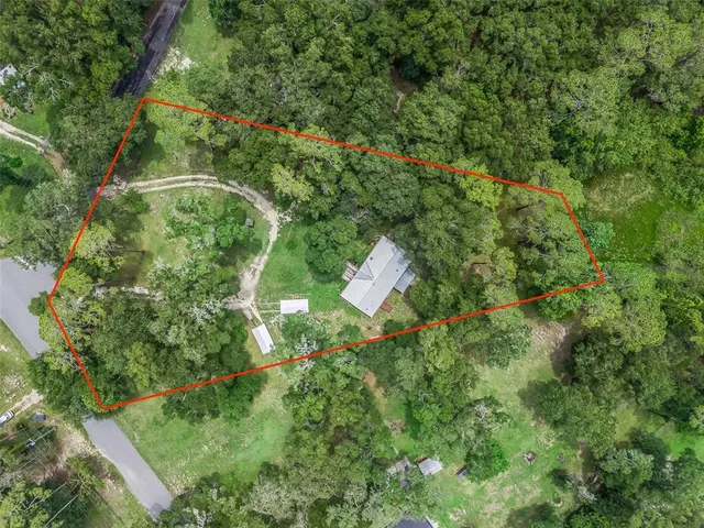 an aerial view of residential houses with outdoor space and trees