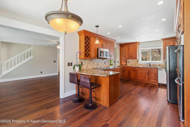 a kitchen with stainless steel appliances granite countertop a refrigerator a stove and a wooden floors