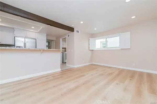 a view of an empty room with window and wooden floor