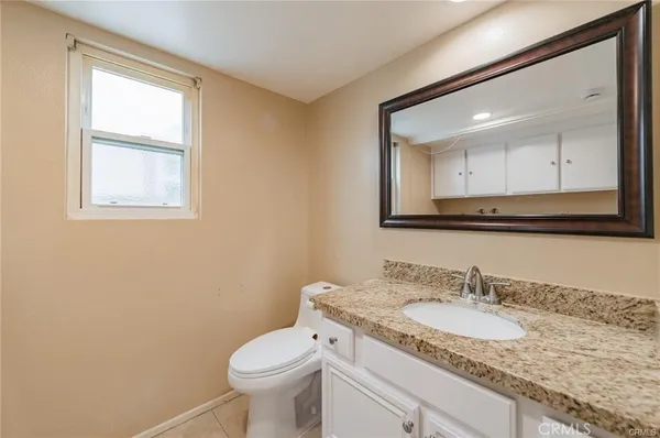 a bathroom with a granite countertop toilet sink and mirror