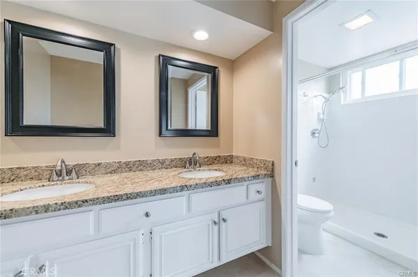 a bathroom with a granite countertop sink a toilet and a mirror