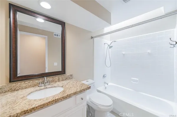 a bathroom with a granite countertop sink a toilet and shower