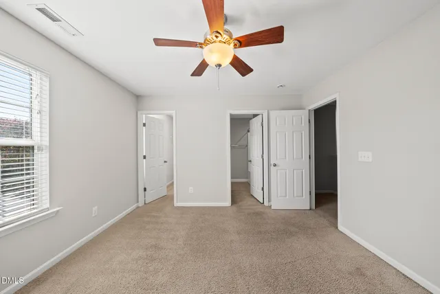 a view of an empty room with window and a ceiling fan