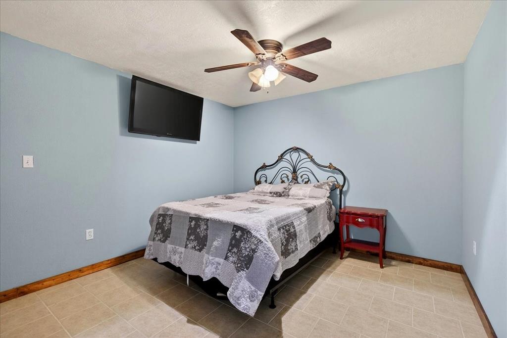 11591 Farm To Market 59 Athens, TX 75751 - Photo 25 of 40 5th bedroom in Basement featuring Light blue painted walls, a ceiling fan with light fixture and tile flooring, closet. This room is also an EMERGENCY SAFE ROOM because of the completely concreted walls and no window.