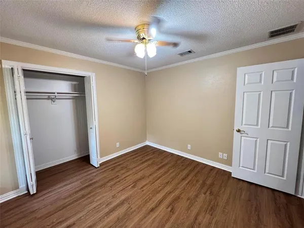 an empty room with wooden floor fan and windows