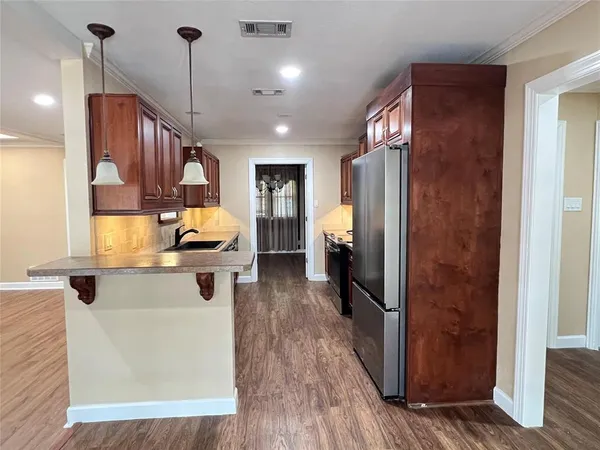 a kitchen with stainless steel appliances granite countertop a refrigerator a sink a stove and a wooden floors