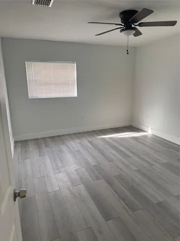 a view of empty room with window and wooden floor