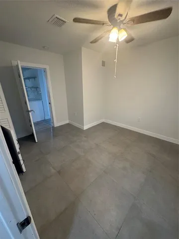 an empty room with a ceiling fan and a window