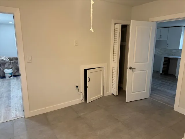 a view of empty room with wooden floor and kitchen