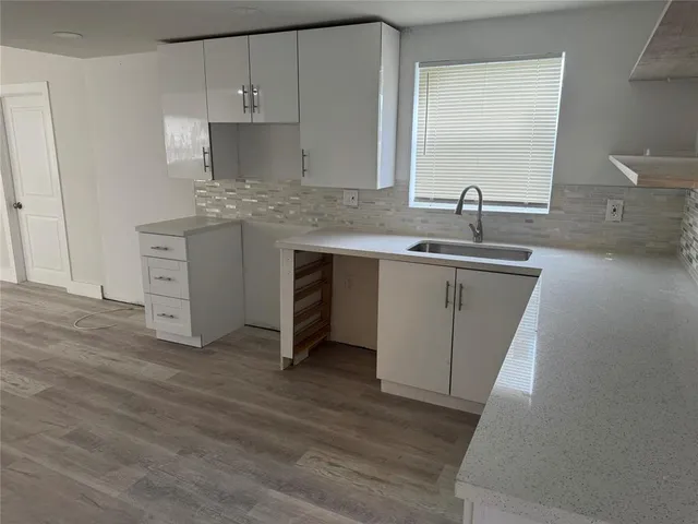 a kitchen with a sink cabinets and wooden floor