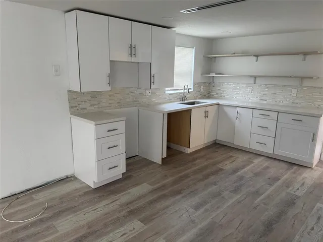 a kitchen with granite countertop a sink cabinets and wooden floor
