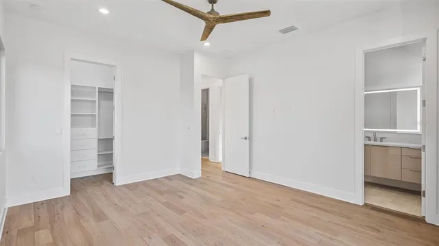an empty room with wooden floor closet and windows