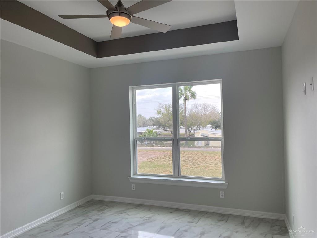 5515 North Crown Point Pharr, TX 78577 - Photo 13 of 15 Empty room with a tray ceiling, light marble finish floors, and ceiling fan