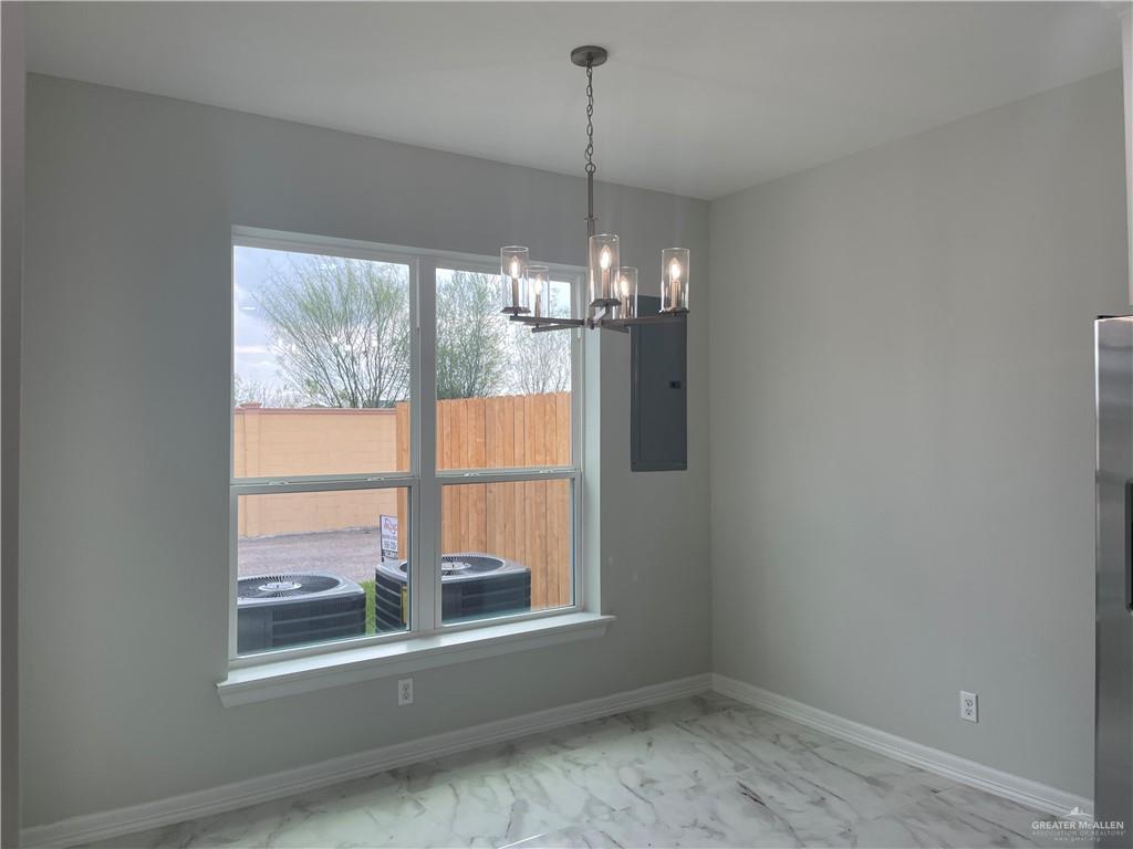 5515 North Crown Point Pharr, TX 78577 - Photo 6 of 15 Unfurnished dining area with light marble finish flooring, electric panel, and a chandelier