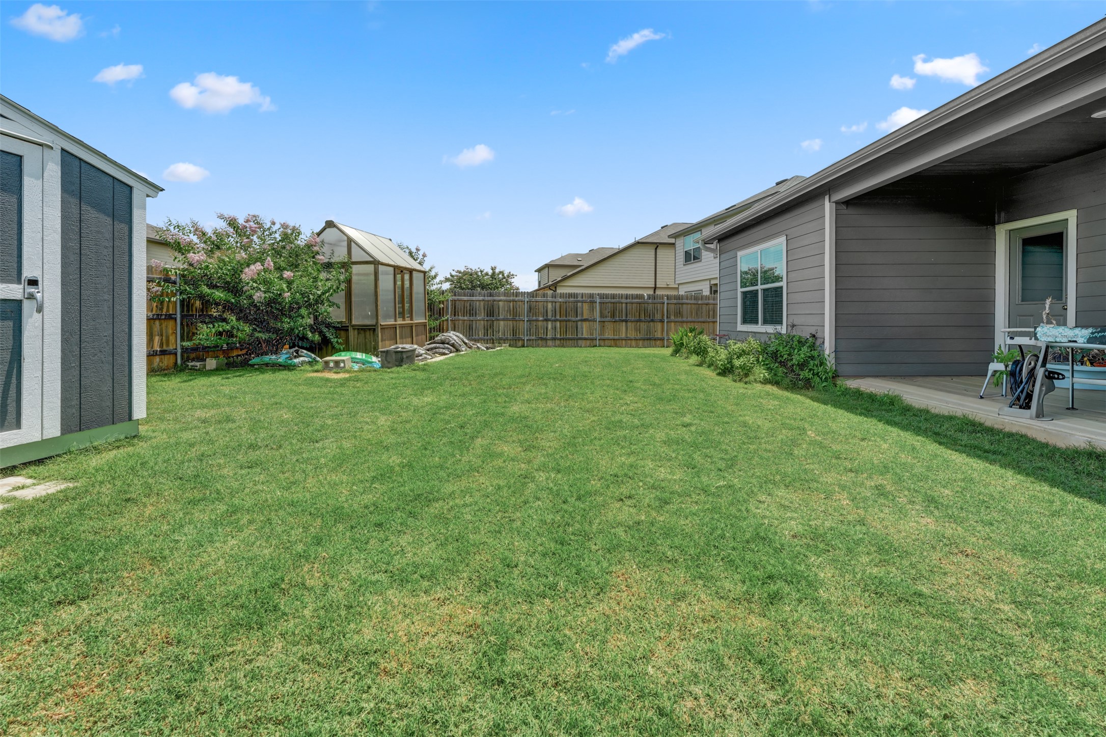 413 Perfect World Loop Jarrell, TX 76537 - Photo 34 of 39 A spacious backyard with a functional greenhouse and covered patio awaits your outdoor pursuits.