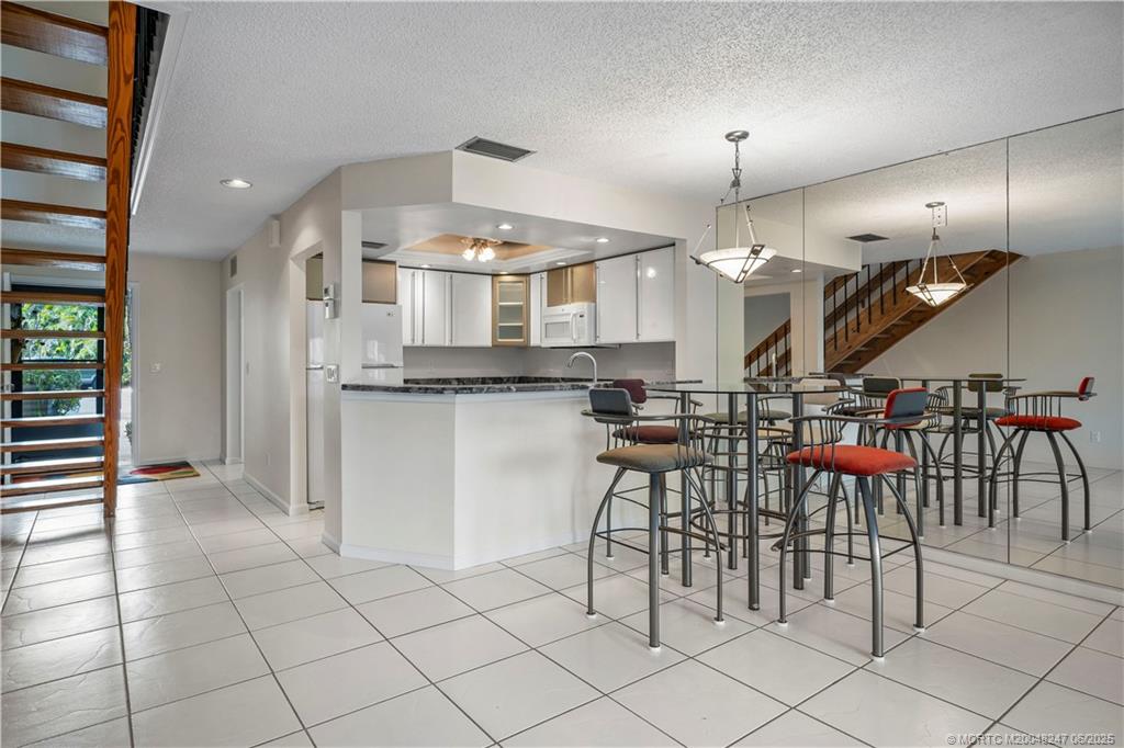 4761 Southeast Binnacle Way, Unit 108 Stuart, FL 34997 - Photo 9 of 43 a kitchen with stainless steel appliances kitchen island granite countertop a refrigerator and a sink