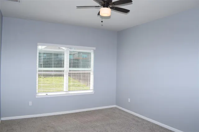 a view of a room that has a window and a ceiling fan