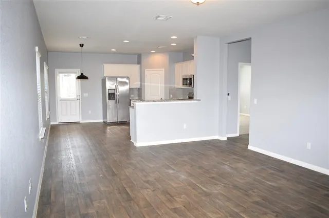 a view of a big room with wooden floor and windows