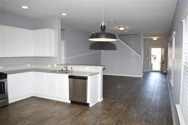 a view of a kitchen with a sink and dishwasher a stove top oven with wooden floor