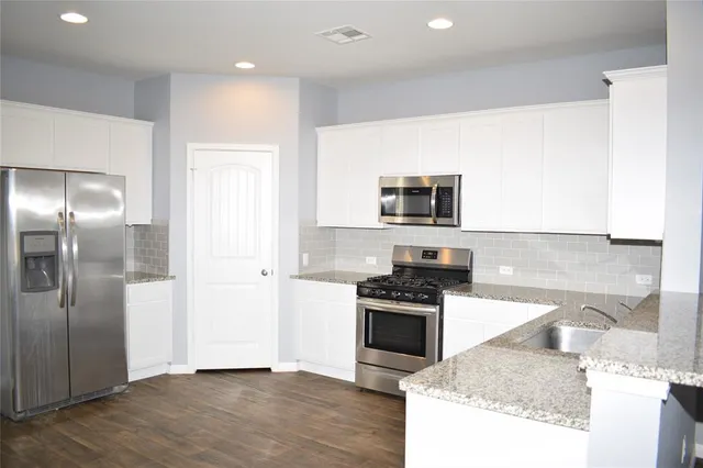 a kitchen with granite countertop a stove top oven and sink