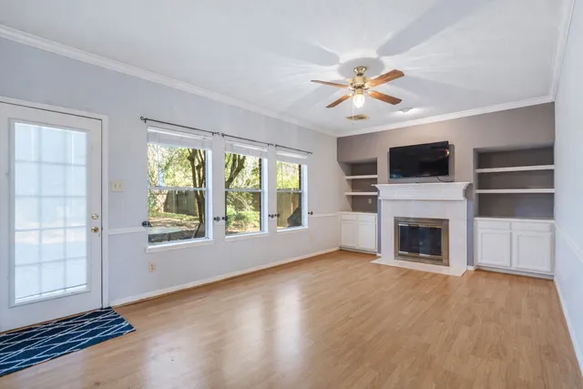 an empty room with windows fireplace and fan