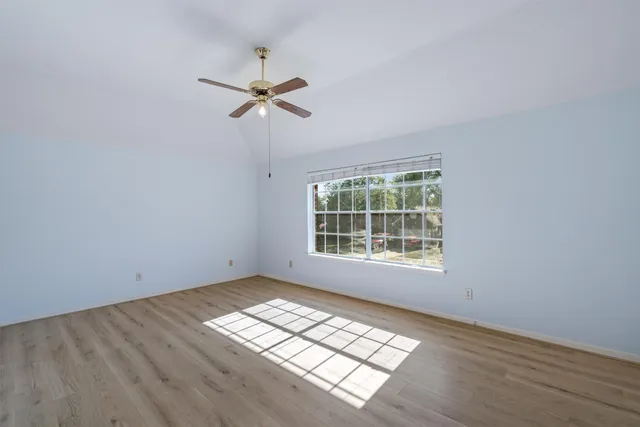 a view of empty room with wooden floor and fan